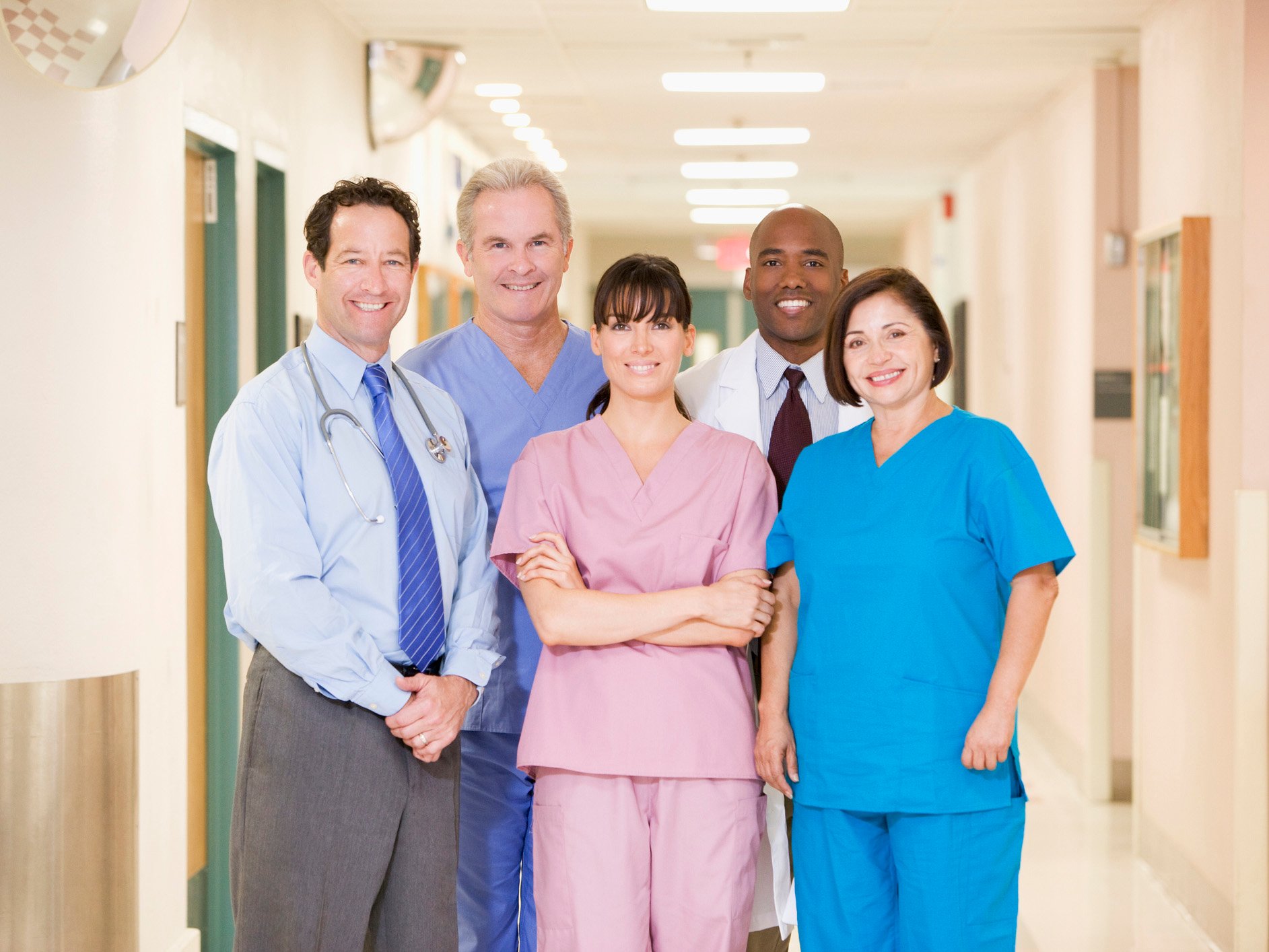 group of five doctors standing together smiling in hospital hallway