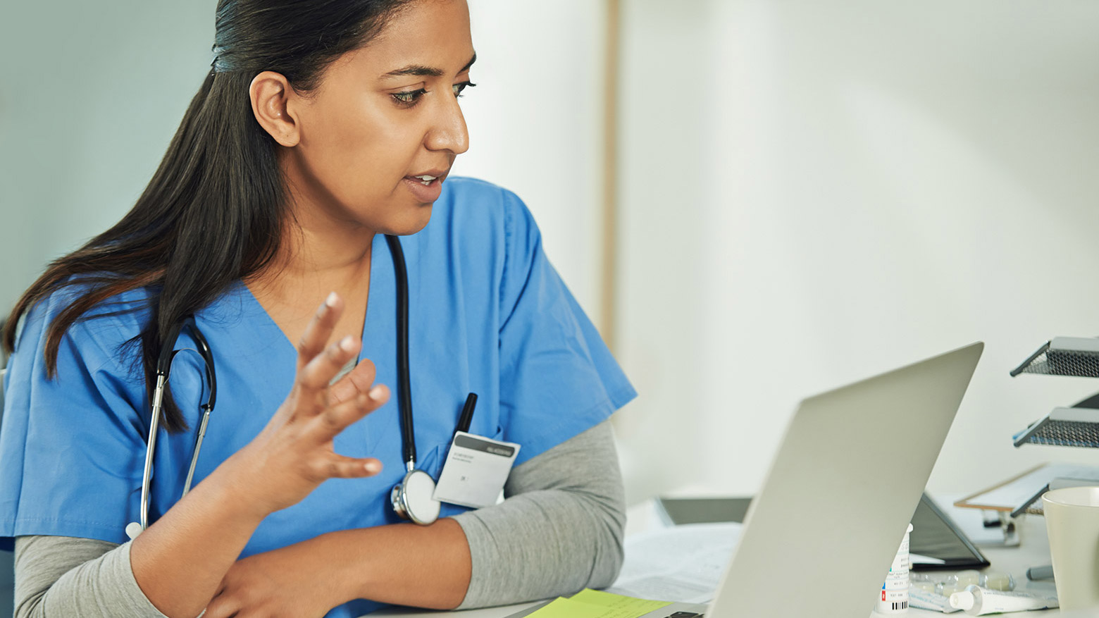 A female doctor speaks for a video call while sitting in front of her laptop