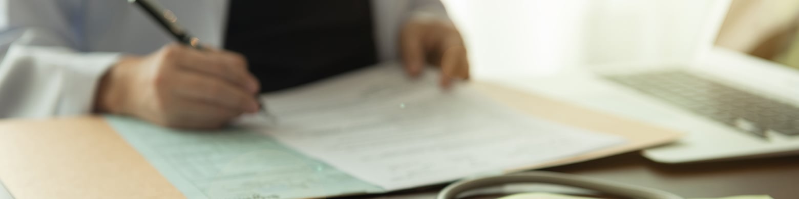 A doctor sits at a desk and fills in paper work