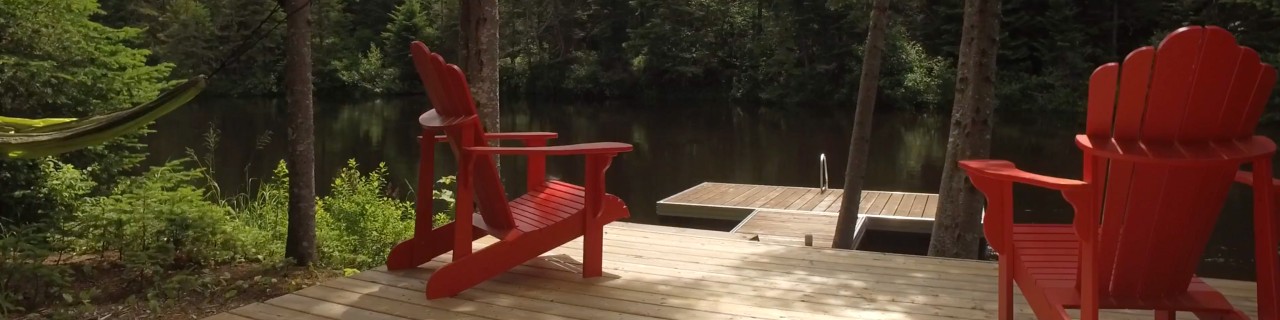 Two Muskoka chairs on a deck  by a lake