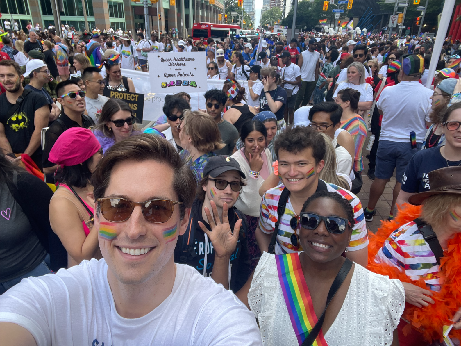 OMA President Dr. Dominik Nowak and President-elect Dr. Zainab Abdurrahman smile in a selfie with a large crowd behind them in a downtown Toronto street.