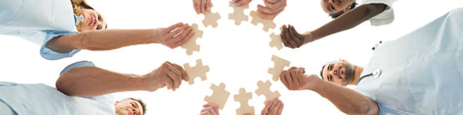 A team of doctors standing in a circle holding pieces of a puzzle.