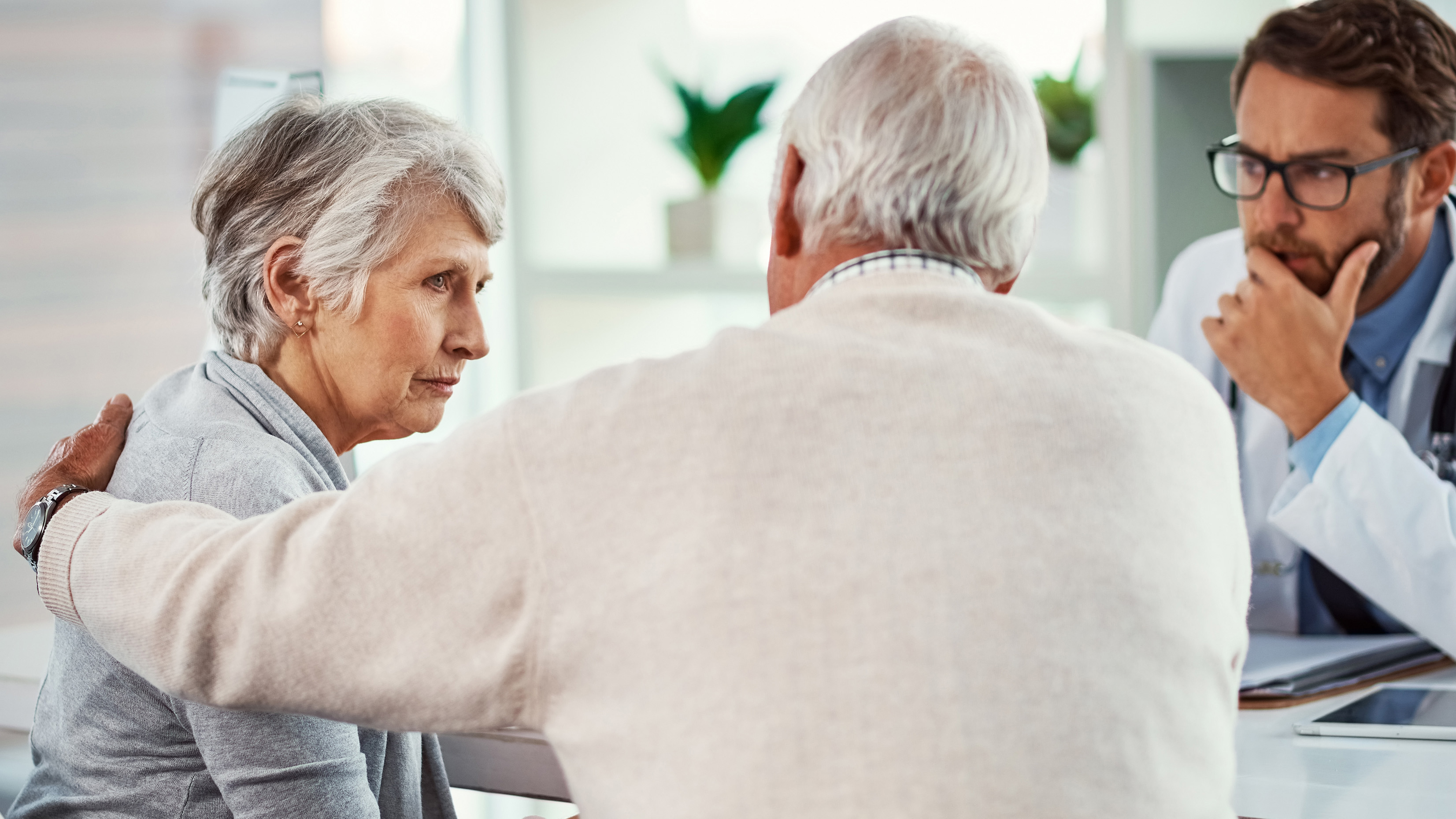 doctor and man comforting older female patient